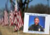 A sign and flags honor Riverdale Police Maj. Greg Barney, who was not wearing a bulletproof vest when he was shot