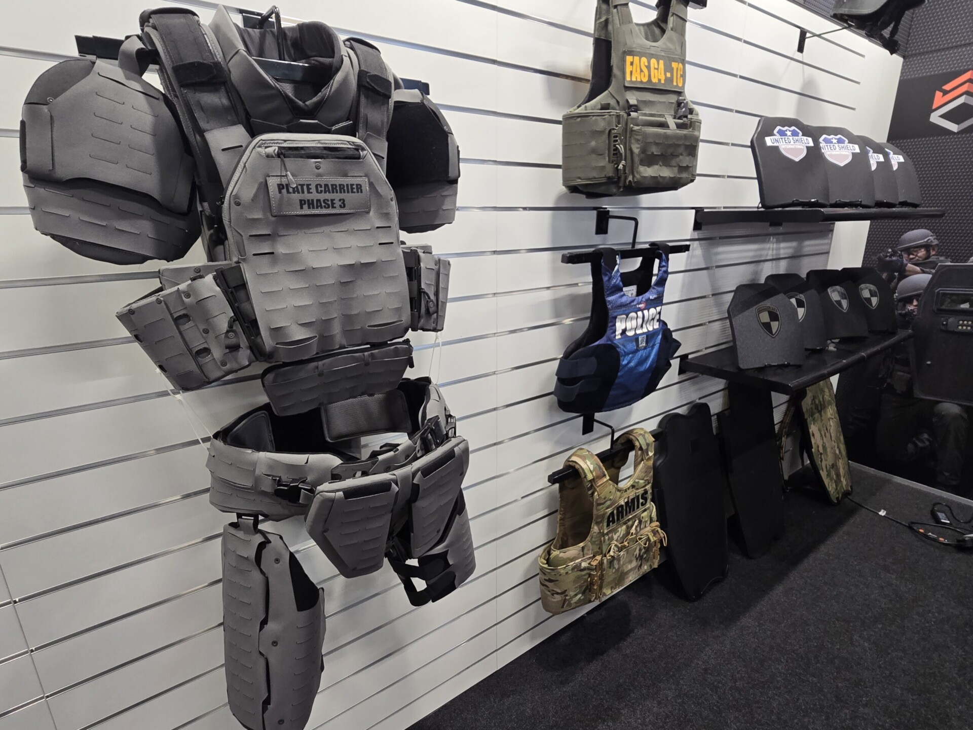 Modern Tactical Body Armor on Display A tactical mannequin wearing modern camouflage body armor and helmet is displayed at a defense exhibition booth, illustrating the latest advancements in body armor innovation and protective gear for military and law enforcement.