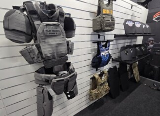 From the Streets to the Lab: How Real-World Threats Are Shaping the Future of Body Armor A tactical mannequin wearing modern camouflage body armor and helmet is displayed at a defense exhibition booth, illustrating the latest advancements in body armor innovation and protective gear for military and law enforcement.